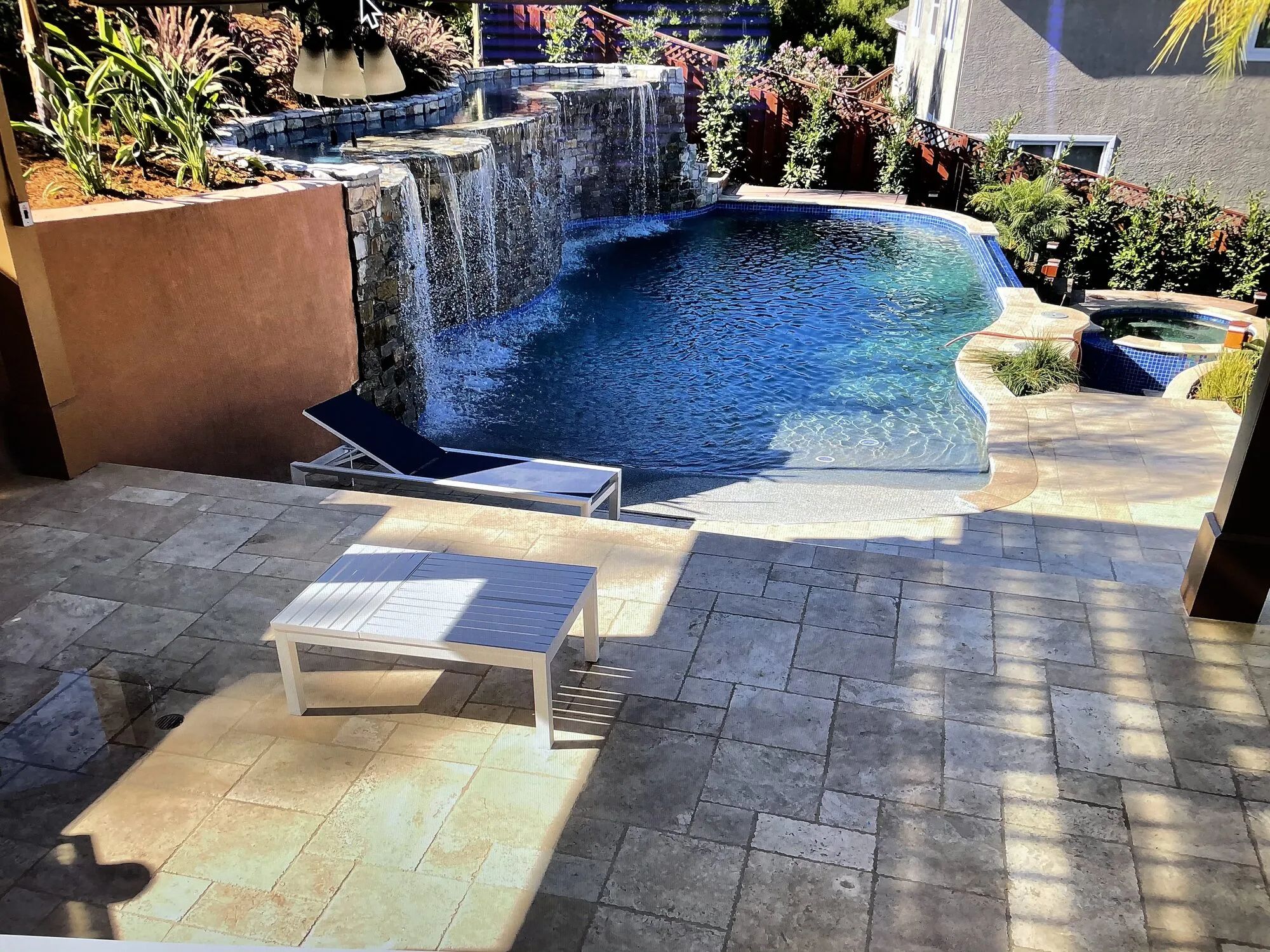 The pool seen across the lower terrace, with a sequence of waterfalls descending from the planted upper levels.