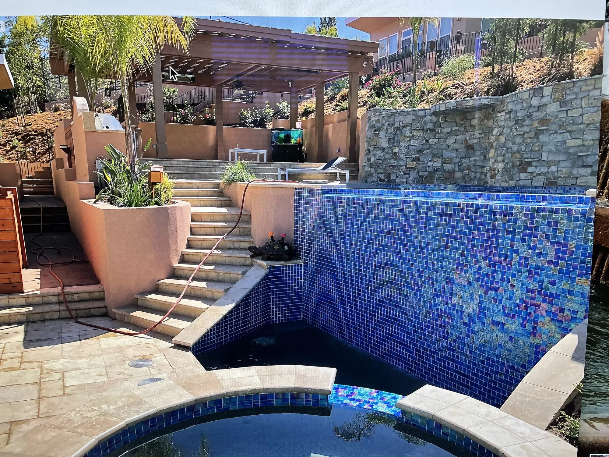 Terraced pools, waterfalls, stone walls, and the upper pavilion aligned across the hillside.